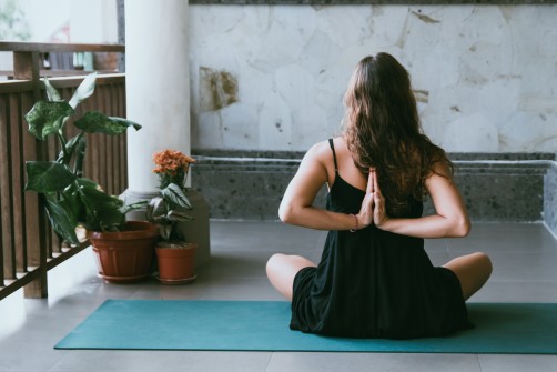 woman touching her back with folded hands